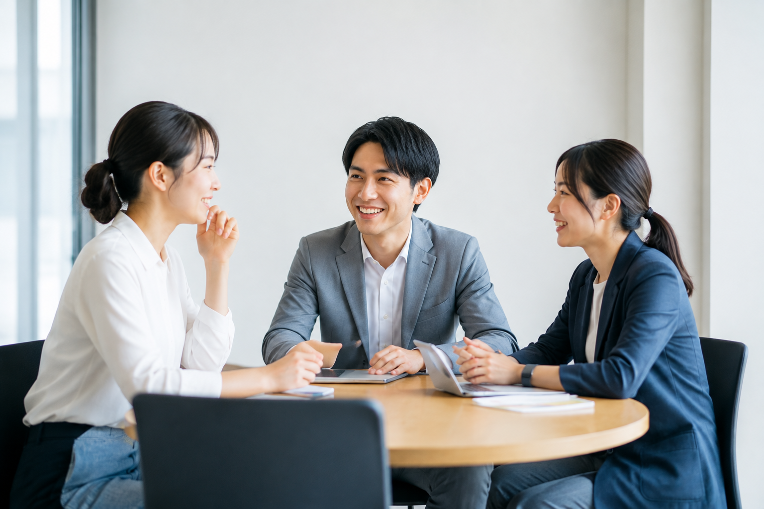 テーブルを囲んで対話する3人
